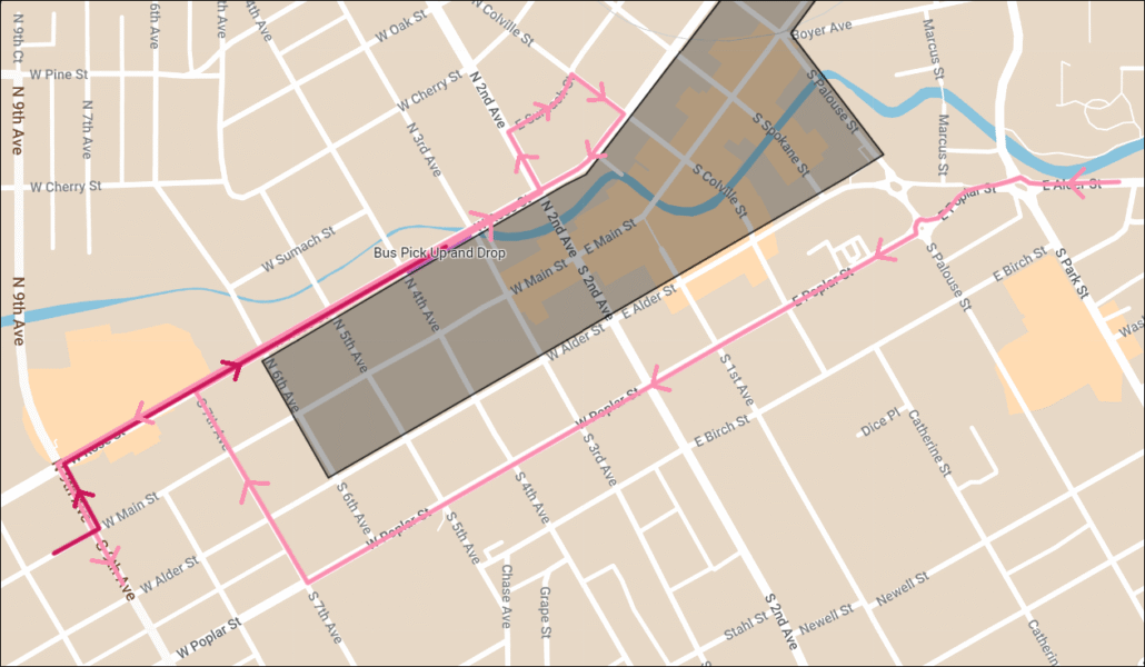 Map showing a bus route in pink with directional arrows through a grid of streets, intersecting a gray-shaded area.